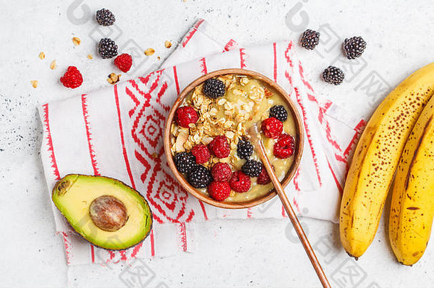 健康的早餐奶昔碗浆果素食主义者鳄梨香蕉冰奶油浆果格兰诺拉麦片木碗前视图