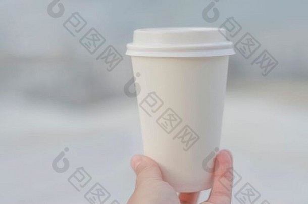 特写镜头女手持有白色纸咖啡杯奶油背景