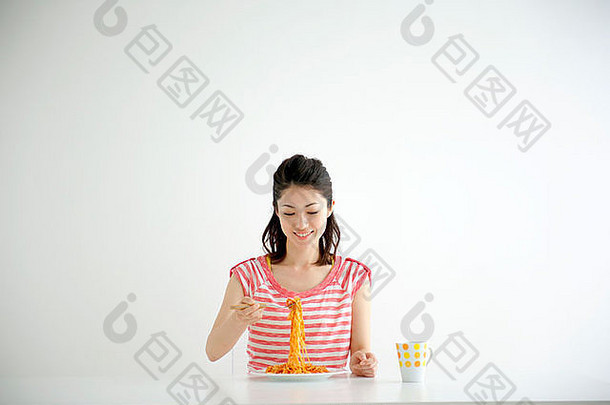 日本大阪县年轻的女人坐着表格吃意大利面微笑