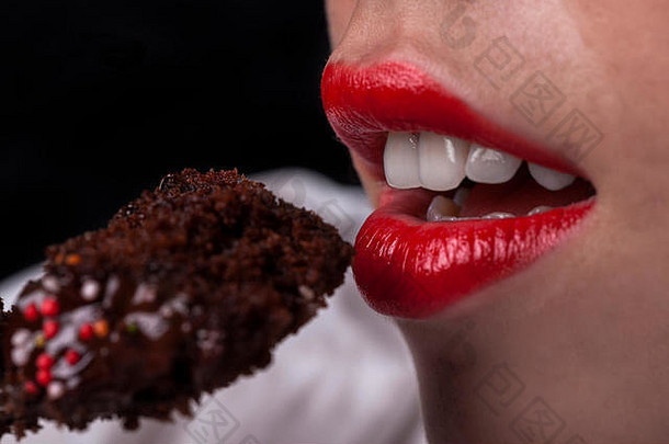 年轻的女孩口红色的嘴唇吃巧克力蛋糕
