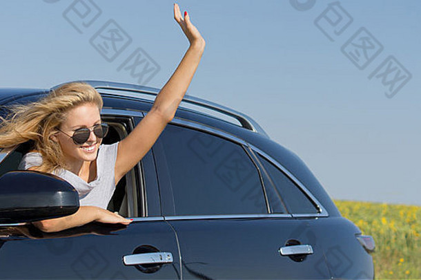 美丽的金发女郎女人太阳镜倾斜挥舞着车窗口
