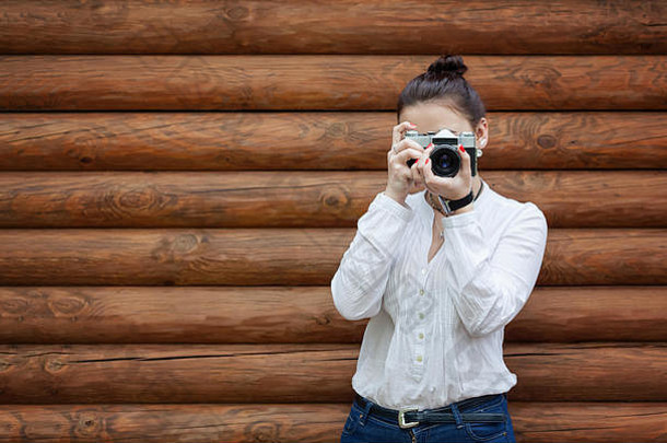 年轻的女孩摄影师白色上衣蓝色的牛仔裤使<strong>照片</strong>复古的电影相机