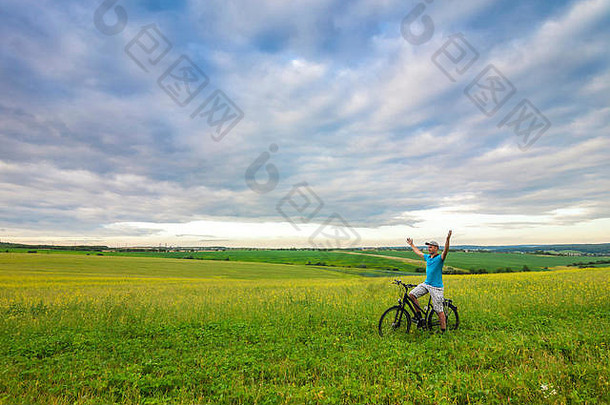 年轻的男人。自行车绿色场阳光明媚的夏天一天