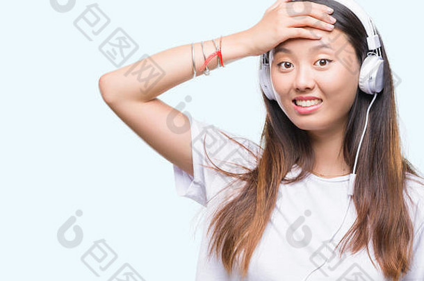 年轻的亚洲女人听音乐穿耳机孤立的背景强调手头震惊了羞愧惊喜脸愤怒的