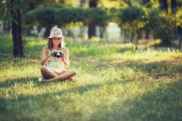 女孩玩照片相机坐着草公园自拍拍摄世界