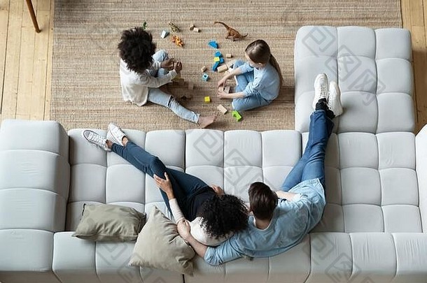 视图父母休息沙发上女儿玩地毯
