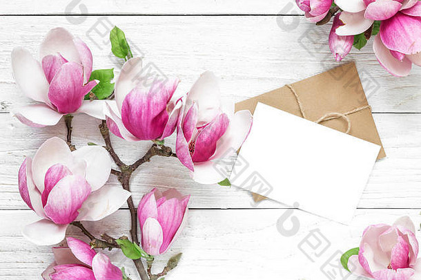 空白白色问候卡粉红色的木兰花信封白色木表格平躺前视图模拟婚礼女人的一天背景