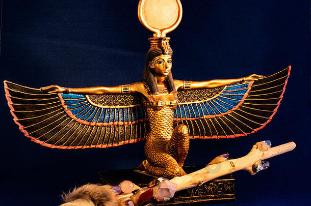 埃及女神伊西斯跪着传统的魔法魔杖使石英紫水晶晶体木羽毛黑暗午夜蓝色的背景