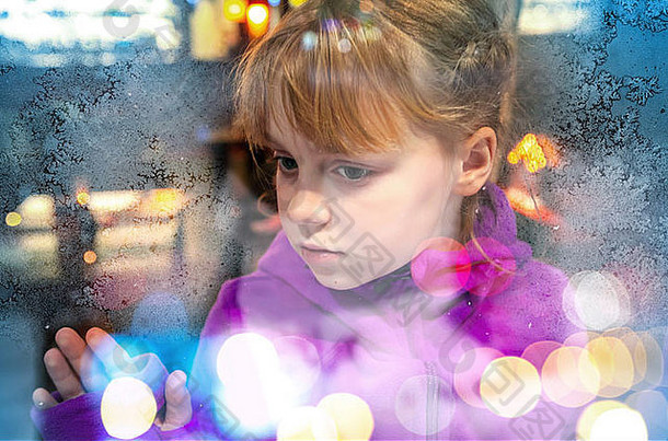 金发碧眼的女孩冻商店窗口玻璃色彩斑斓的模糊灯