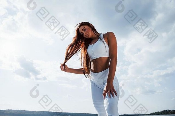 浅黑肤色的女人健身女人站在户外白色<strong>运动</strong>型衣服多云的天空白天