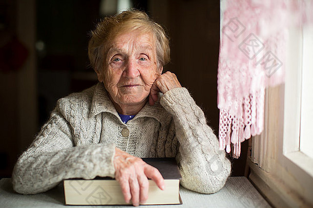 上了年纪的女人坐着书窗口