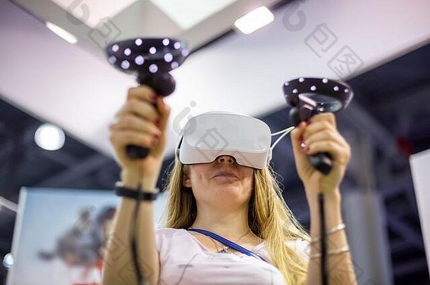 年轻的高加索人女孩虚拟现实头盔持有控制棒手戏剧游戏字体。视图软焦点关闭