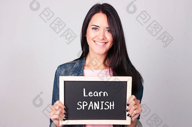 年轻的美丽的女人持有黑板学习西班牙语