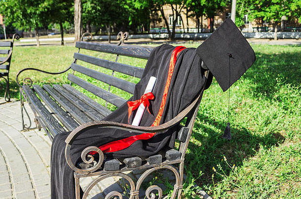 毕业帽他黑色的流苏地幔学位纸公园板凳上