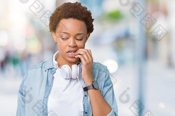 年轻的非洲美国女人穿耳机孤立的背景强调紧张手口咬指甲焦虑个困难