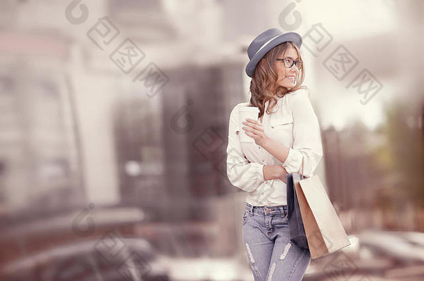 快乐年轻的时尚女人购物袋享受喝咖啡购物持有咖啡城市背景