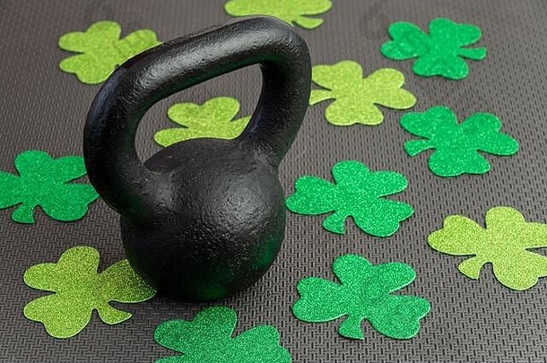 黑色的铁壶铃绿色三叶草黑色的健身房地板上假期健身