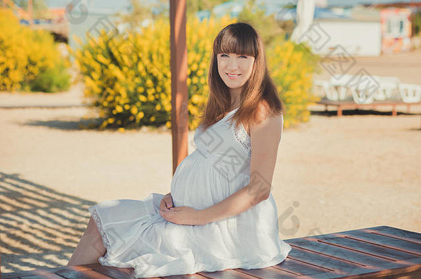 真正的可爱的怀孕了夫人女人白色艾里衣服走沙子海滩木调色板桥持有肚子腹部有吸引力的美丽的年轻的女孩