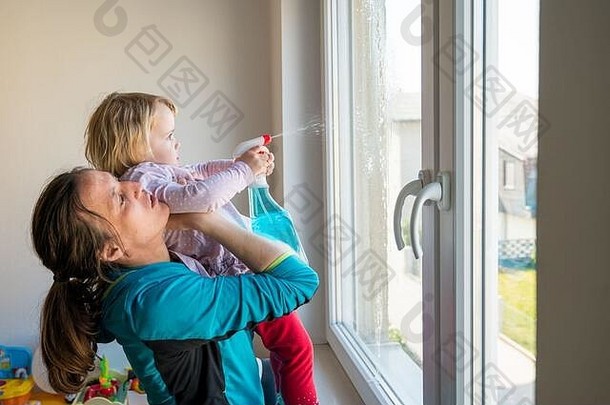 可爱的女孩帮助妈妈。清洁窗户