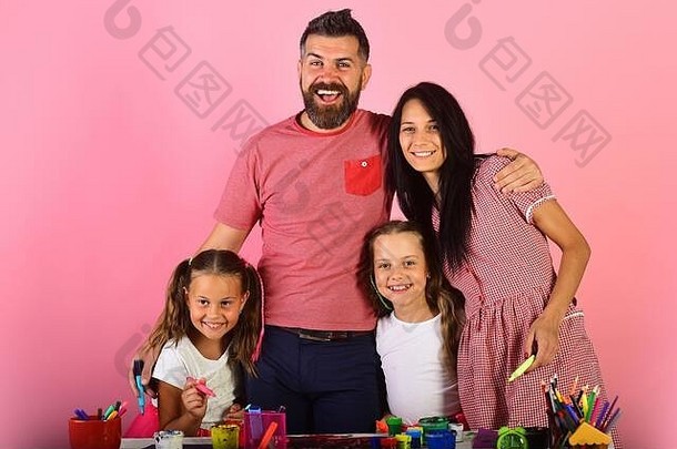 女孩男人。女人快乐脸艺术桌子上父母孩子们油漆标记微笑粉红色的背景艺术家家庭拥抱吸引了家庭休闲时间艺术概念