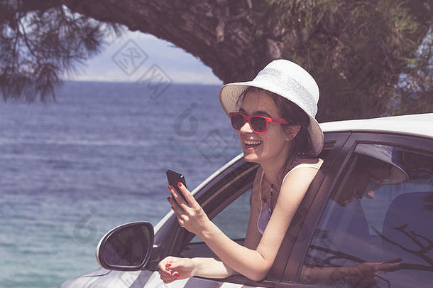 快乐女倾斜车窗口聪明的电话海洋背景旅行假期概念