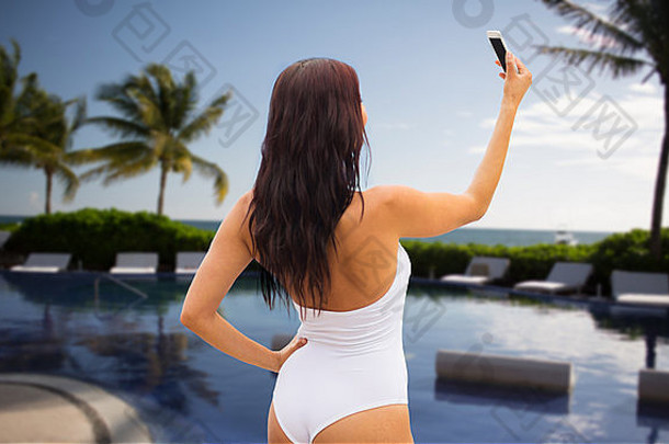 年轻的女人采取自拍智能手机海滩
