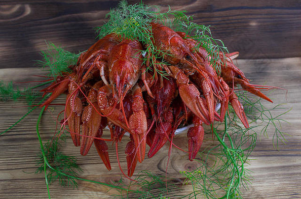 板红色的煮熟的小龙虾爪子茴香木背景