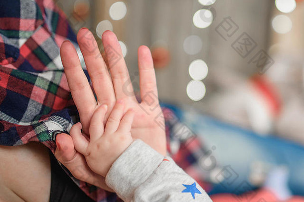 婴儿的手持有母亲的手背景散焦一年的花环圣诞节奇迹一年圣诞节一年