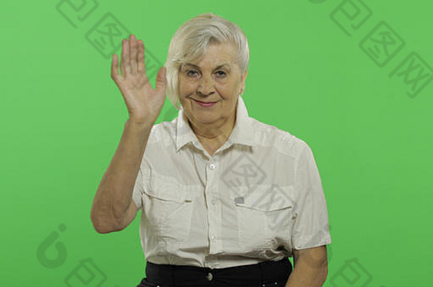 上了年纪的女人挥舞着相机微笑漂亮的祖母白色衬衫的地方标志文本浓度关键绿色屏幕背景