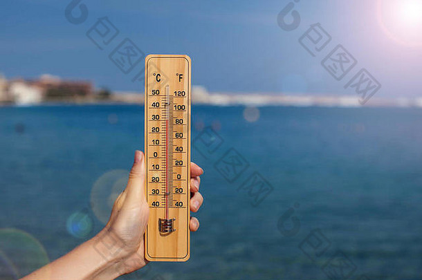 手女人持有温度计海滩背景夏天气候天气概念