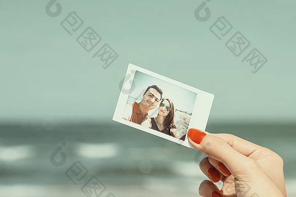 女孩手持有复古的即时<strong>照片</strong>年轻的快乐夫妇海滩
