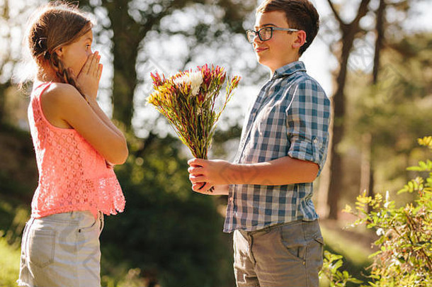 快乐男孩女孩站公园男孩给花束花兴奋女孩表达惊喜建议的男朋友