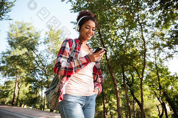 图像快乐的年轻的非洲女人走在户外公园听音乐<strong>聊天</strong>电话