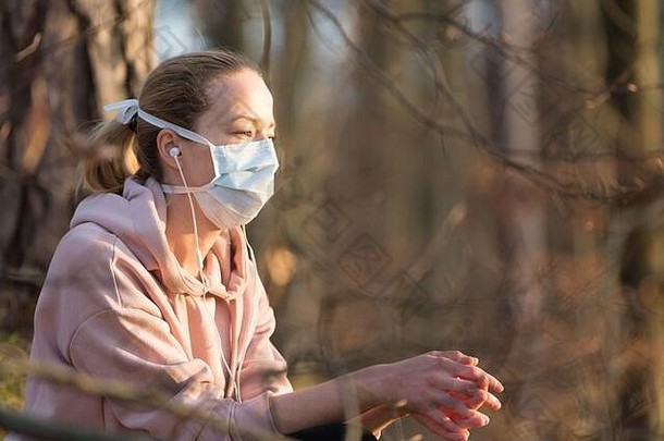 肖像高加索人运动女人穿医疗保护脸面具放松自然听音乐电晕病毒科维德