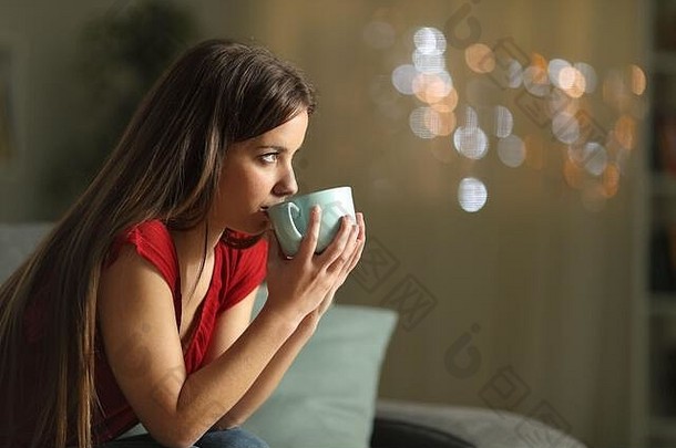 一边视图肖像女人喝咖啡坐着沙发上晚上首页