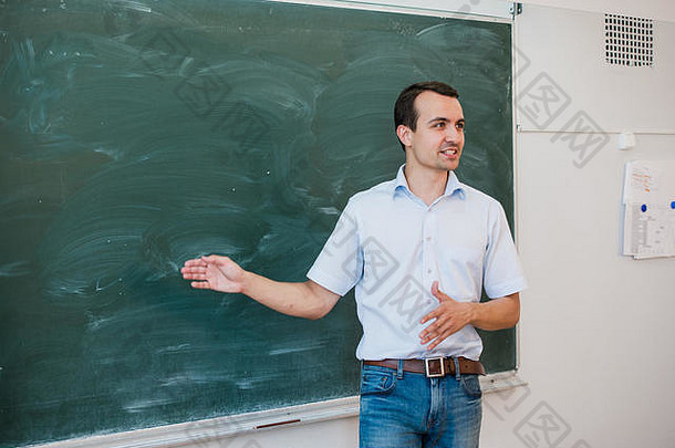 肖像年轻的英俊的学生老师类指出空白黑板会说话的微笑