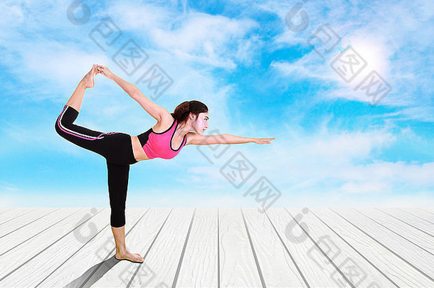 年轻的女人瑜伽锻炼木地板上天空