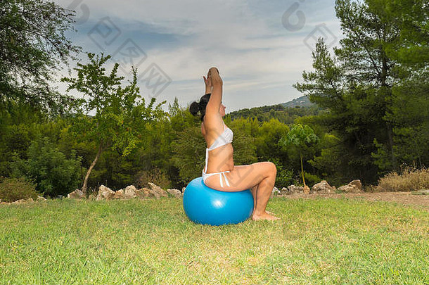 女人坐着健身球伸展运动身体