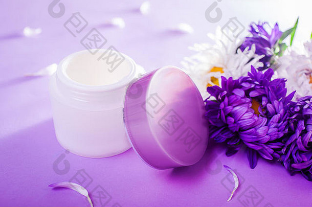 Jar奶油包围花紫色的背景有机化妆品自然成分身体护理