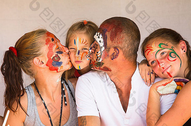 快乐家庭年轻的夫妇接吻年轻的婴儿女儿玩油漆