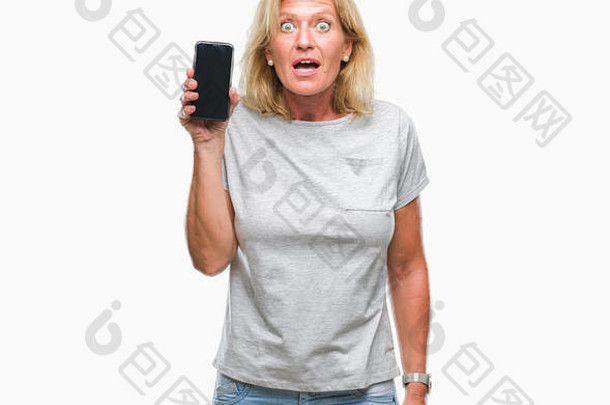 中间年龄金发女郎女人显示空白屏幕智能手机孤立的背景害怕冲击惊喜脸害怕兴奋恐惧