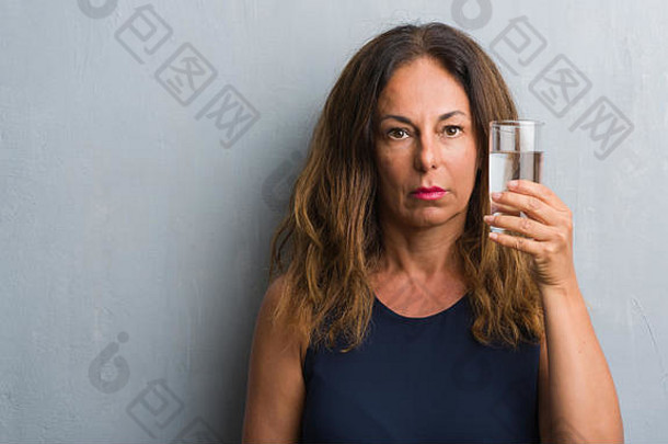 中间年龄拉美裔女人喝玻璃水自信表达式聪明的脸思考