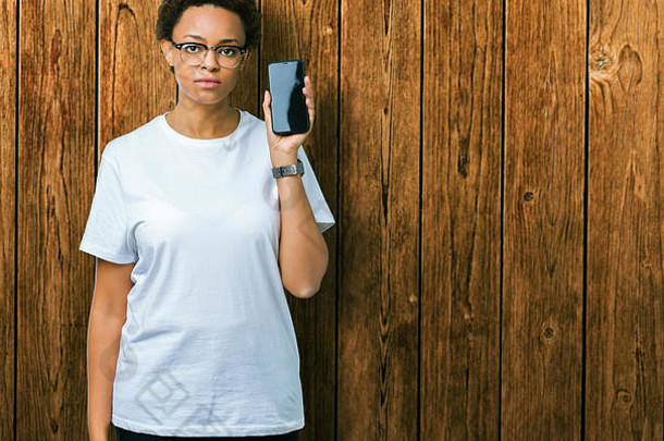 年轻的非洲美国女人显示智能手机<strong>屏幕</strong>孤立的背景自信表达式聪明的脸思考