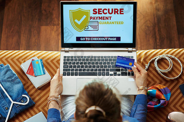 上视图时尚的女人蓝色的上衣信贷卡购买安全互联网移动PC坐着窟现代生活房间