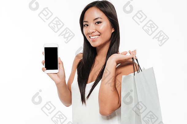 关闭肖像微笑年轻的休闲亚洲女人显示空白屏幕移动电话站购物袋孤立的白色引入