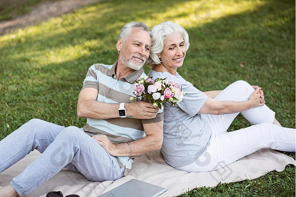 快乐岁的结婚了夫妇坐着草公园
