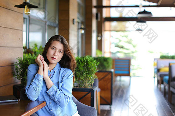 caucasuian女人休息咖啡馆房间植物穿牛仔裤衬衫