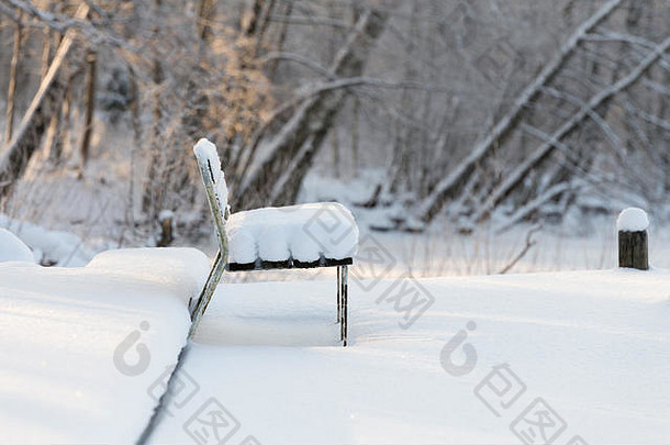 孤独的板凳上覆盖厚完整的雪冻河磨砂树