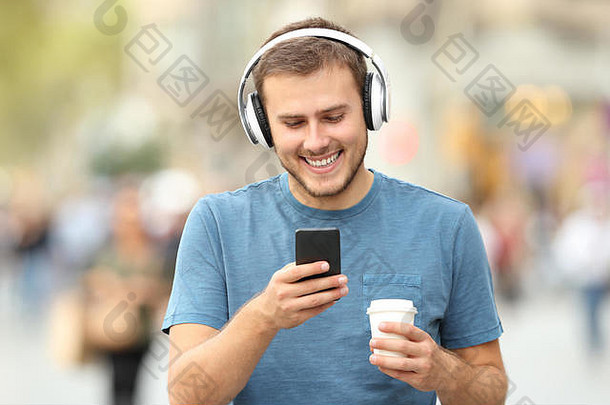 前面视图快乐男人。走听音乐穿耳机持有喝街
