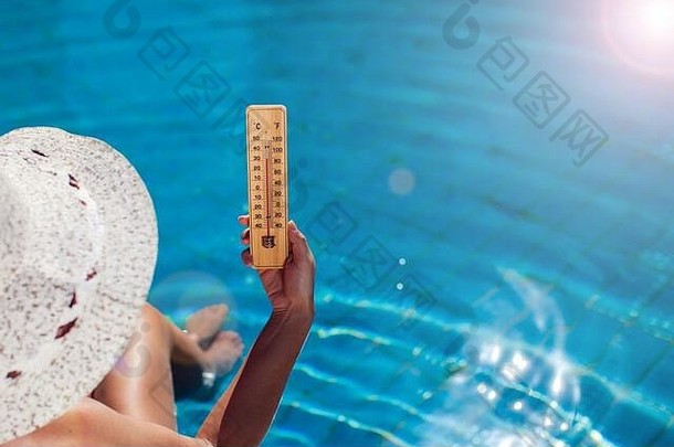 女人持有温度计蓝色的池背景热天气夏天概念